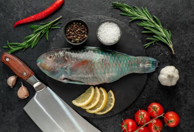 Siyah zemin üzerinde limonlu çiğ balık ve biberiye.