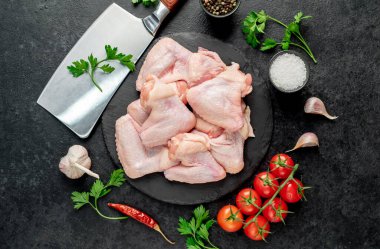 Siyah arka planda baharatlı ve otlu çiğ tavuk kanatları.