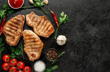 Baharatlı ızgara biftek ve siyah arka planda otlar.