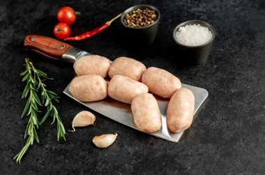 Siyah arka planda baharatlı ve otlu çiğ tavuk sosisi..