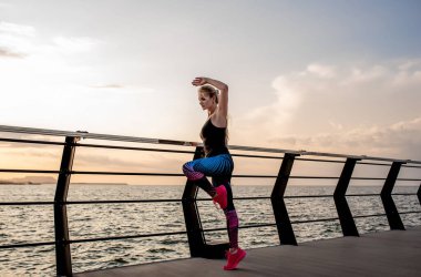 Genç bir kadın şafak vakti okyanus manzaralı sette yoga yapıyor..