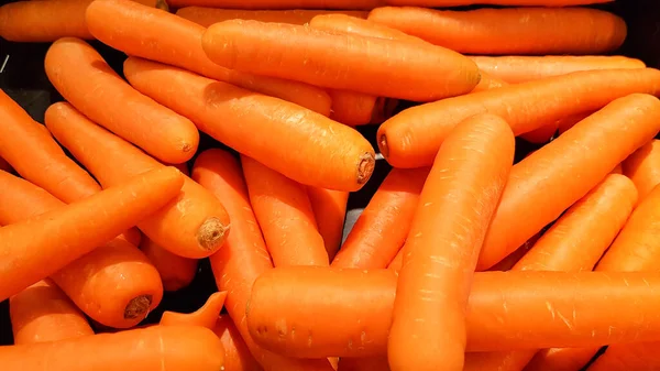 Carrots placed in a stall for sale.Macro Photo spring food vegetable carrot. Texture background of fresh large orange carrots. Product Image Vegetable Root Carrot.