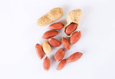 Beyaz arka planda kırmızı ve soyulmuş fıstık. Bir fıstık soyuldu, içinde kırmızı bir tohum ortaya çıktı..