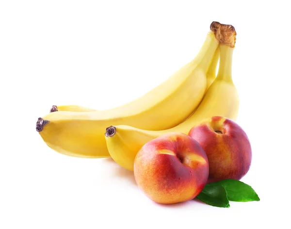 Rijpe bananen en perziken op wit. — Stockfoto