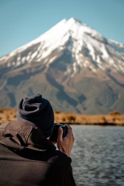 Adam Taranaki Dağı 'nda kamerayla fotoğraf çekiyor. Dikey fotoğrafçılık