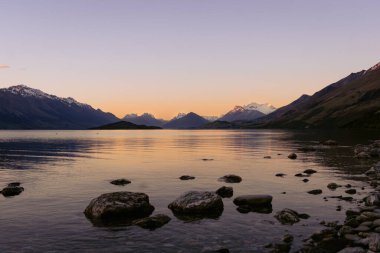 Dramatic sunset in Lake Wakatipu with the amazing view of snowy peaks. Otago, New Zealand.