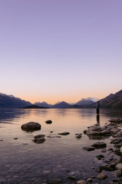 Wakatipu Gölü 'nün içindeki adam dağ sırasının içinde gün batımını seyrediyor. Otago, Yeni Zelanda.