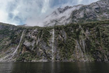 Milford Sound 'da okyanusun ortasındaki büyük kaya duvarındaki şelaleler. Yeni Zelanda 'nın ünlü hedefi.
