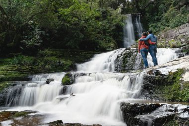 Couple embracing each other at McLean falls, located in Otago Region of New Zealand.
