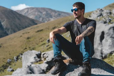 Castle Hill 'de bir kayanın üzerinde oturan beyaz bir adam. Canterbury Bölgesi, Yeni Zelanda. Gerçek İnsanlar kavramı.