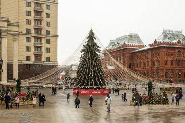 Moskova, Rusya-Aralık, 20, 2020: Okhotny Ryad 'daki şehir merkezinde çelenkli Noel ağacı bulutlu bir kış gününde Kızıl Meydan yakınlarında tarihi mimarinin arka planına karşı
