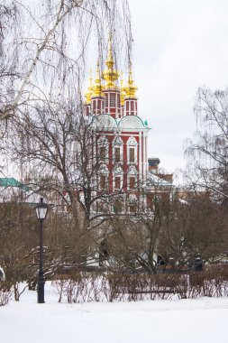 Moskova, Rusya-Ocak, 3 Ocak 2021: Novodevichy Manastırı 'nın tarihi mimarisi ve bulutlu bir kış gününde beyaz kar ve çıplak ağaçlar