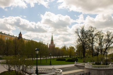 Moskova, Rusya-Mayıs, 5, 2021: güneşli bir bahar gününde Alexander Garden 'ın panoramik manzarası ve Borovitsky Kulesi ile yeşil ağaçlar ve sarı komik saray ve Kremlin duvarı.