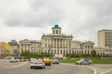 Peshkov Evi 'nin beyaz tarihi sarayının panoramik görüntüsü ve bir bahar günü bulutlu bir gökyüzünün arka planında geçen arabalar. Moskova Rusya 'da ünlü bir yer.