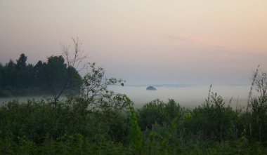 Dramatik manzara, yaz sabahının erken saatlerinde, çarpıcı bir eğimle çayırların, ağaçların ve boşluğun üzerinde sis ve gökyüzü kopyalanacak.