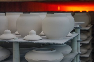 Moskova bölgesindeki bir porselen fabrikasına yakın çekim yapmak için egzoz fırınına yerleştirilmiş kapaklı beyaz seramik tencereler.