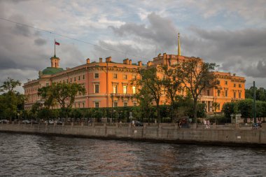 Saint PETERSBURG, RUSSIA-JULY, 16, 2021: Fontanka Nehri seti üzerindeki turuncu Mikhailovsky Şatosu 'na bir yaz akşamı gün batımında ve kopyalamak için bir alan