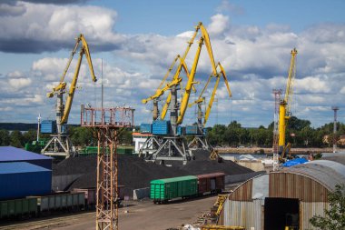 VYBORG, Leningrad REGION, RUSSIA-JULY, 19, 2021: Bulutlu bir yaz gününde körfezin kıyısında yüklenen sarı iskele vinçleri