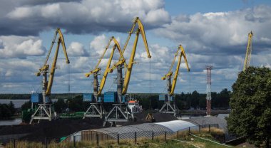 Mavi bulutlu gökyüzünün arka planında sarı kargo vinçleri