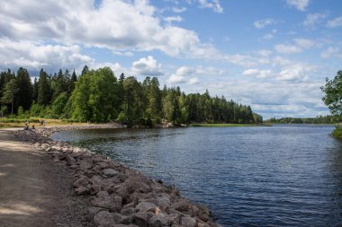 Güneşli bir yaz gününde Vyborg Rusya 'daki Monrepos Parkı' nda çarpıcı bulutlu bir gökyüzünün arka planında yeşil çimenler ve ağaçlarla çevrili güzel bir manzara.