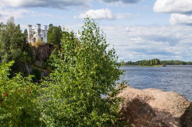 VYBORG, Leningrad REGION, RUSSIA-JULY, 19, 2021: Ludwigsburg 'daki Ludwigstein Adası' ndaki beyaz taş şapeli ve Monrepos Park 'taki yaz bulutlu bir günde ağaçların yeşil yaprakları.