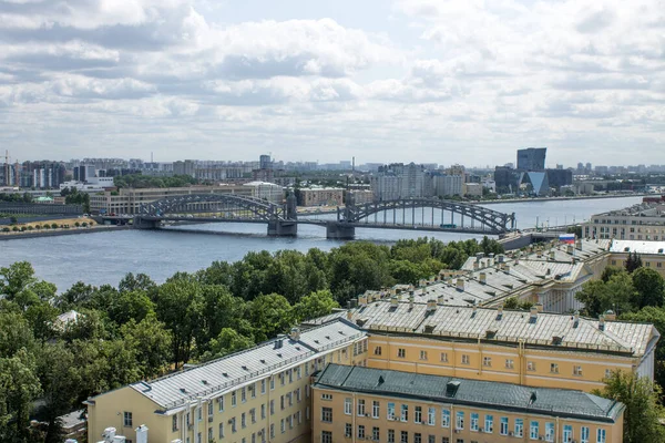 2021年7月20日ロシア サンクトペテルブルク ボルシェフスキンスキー金属橋とスモルニーの鐘楼から晴れた夏の日に家の屋根とネヴァ川のパノラマの上の景色 — ストック写真