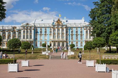 PUSHKIN, Leningrad REGION, RUSSIA-JULY, 21, 2021: Güneşli bir yaz gününde Tsarskoye Selo 'da güzel bitki yatakları ve ağaçları olan muhteşem mavi ve beyaz Catherine Sarayı