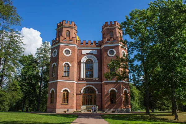 PUSHKIN, Leningrad REGION, RUSSIA-JULY, 21, 2021: Tsarskoye Selo Parkı 'nda güneşli bir yaz gününde ağaçların yeşil yaprakları arasında kırmızı tuğla tarihi pavyon cephaneliği