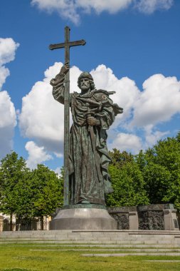 Rusya 'da güneşli bir yaz günü, başkentin tarihi merkezinde, parlak mavi bulutlu bir gökyüzünün arka planında Hıristiyan haçı bulunan Prens Vladimir için bronz bir anıt.