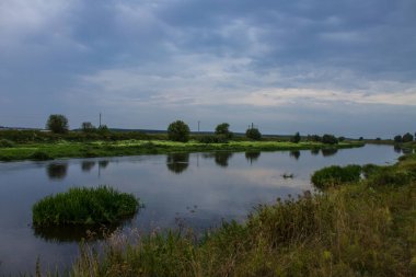 Güzel bir manzara - dramatik bir gün batımı gökyüzü ve yansıması olan bir nehir ve çimen ve ağaçlardan oluşan siluetler ve kopyalanacak bir yer
