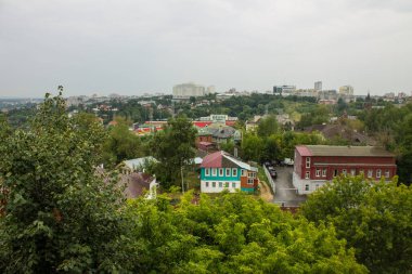 VLADIMIR, RUSSIA-AUGust, 11, 2021: Eski şehrin tarihi binalarının çatılarının panoramik manzarası ve bulutlu bir yaz gününde ağaçların yemyeşil yaprakları