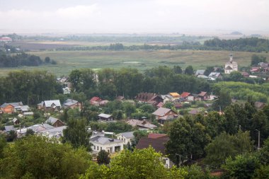 Bulutlu bir yaz gününde evlerin çatıları ve ağaçların yeşil yapraklarıyla tarihi Suzdal kasabasının panoramik manzarası.