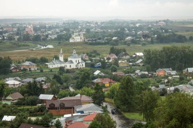 Bulutlu bir yaz gününde evlerin çatıları ve ağaçların yeşil yapraklarıyla tarihi Suzdal kasabasının panoramik manzarası.