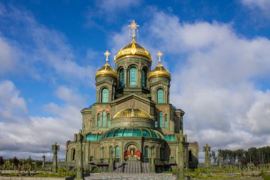 KUBINKA, MOSCOW REGION, RUSSIA-AUGust, 22, 2021: Rus Silahlı Kuvvetleri 'nin modern ana tapınağının ön cephesi Vatanseverlik Parkı' nda mavi bulutlu bir gökyüzüne karşı altın kubbeler.