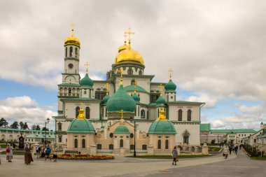 Güneşli bir yaz gününde Yeni Kudüs 'te altın kubbeli beyaz taş kiliselerin ünlü mimari topluluğu Istra Moskova bölgesinde dramatik bulutlarla dolu açık mavi bir gökyüzüne karşı.
