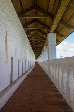Uzun, dar bir galeri, güneşli bir günde Moskova bölgesinde Yeni Kudüs 'teki manastırın beyaz taş kale duvarında yayalara ait ahşap bir yoldur.
