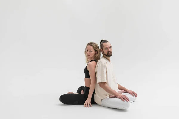 Stüdyoda temas yogası yapan birkaç genç insan. Psikolojik terapi sırasında erkek ve kadın birbirlerine yaslanırlar.
