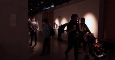 Müze ziyaretçileri maske takmış heykel sergisinde turneye çıkıyorlar.