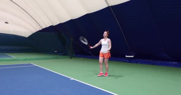Žena v akci na vnitřním hřišti hrát tenis a porazit míč — Stock video