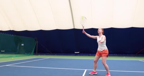 Kvinna i aktion på inomhus domstol spelar tennis och slå bollen — Stockvideo