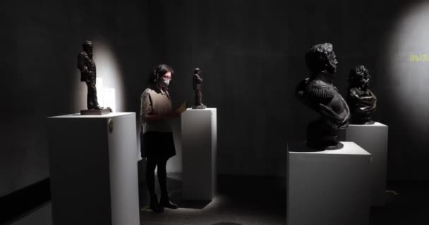 동상 전시회를 관람하고 있는 박물관 방문객들의 얼굴에는 마스크를 쓴 채 — 비디오