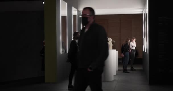 동상 전시회를 관람하고 있는 박물관 방문객들의 얼굴에는 마스크를 쓴 채 — 비디오