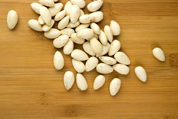 Blanched almonds scattered on a wooden board — Stock Photo, Image
