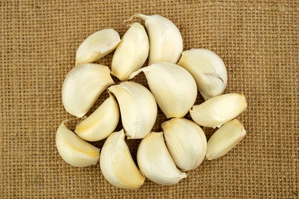 Pile of garlic cloves on a sack cloth background — Stock Photo, Image