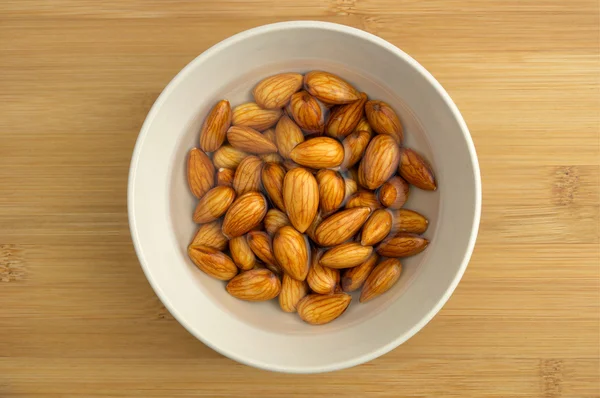 Almonds soaking in a bowl of water — Stock Photo, Image