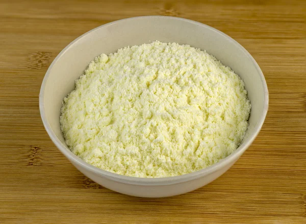 Bowl full of white milk powder against a wooden background — Stock Photo, Image