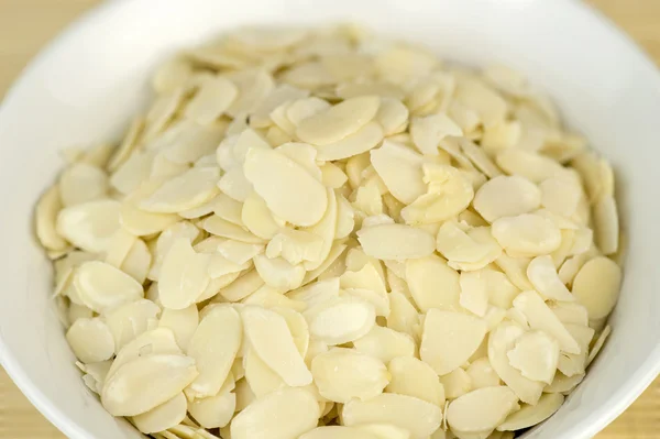 Almond slices in bowl on wooden background — Stock Photo, Image