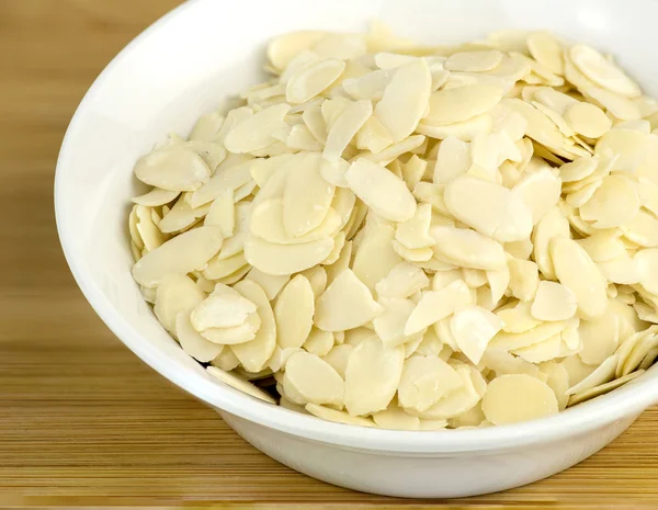 Macro closeup of fresh cut almond flakes in white bowl — Stock Photo, Image