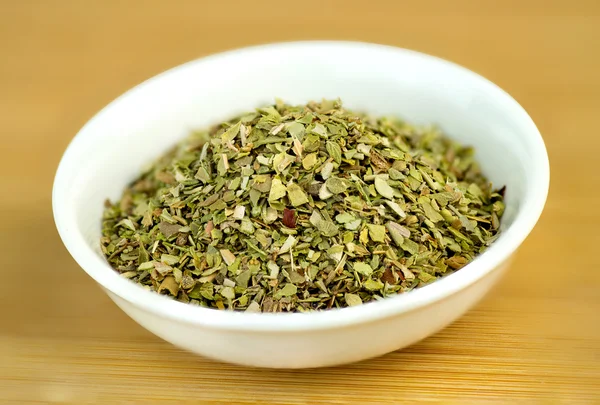 Dehydrated oregano macro in white bowl on wooden background — Stock Photo, Image