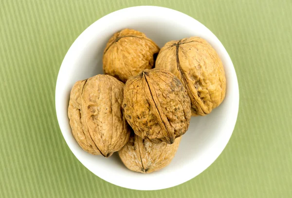 Орехи в миске на зеленом фоне — стоковое фото